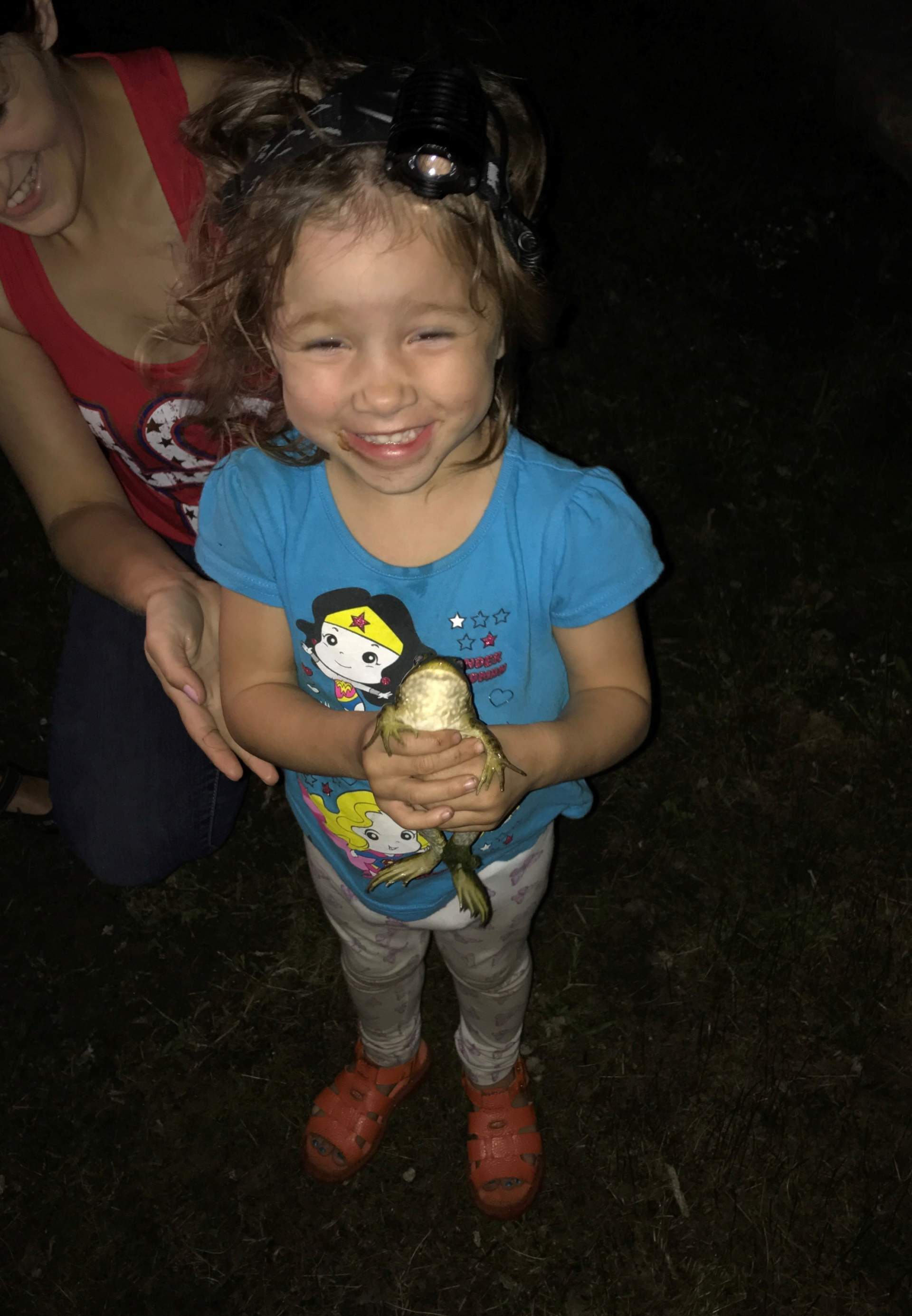 little girl with bullfrog outside herping at night